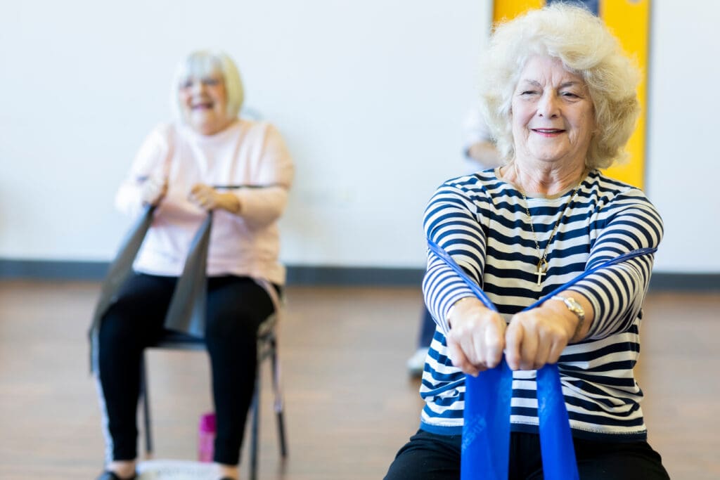 Two women undertaking a fitness class with bands.