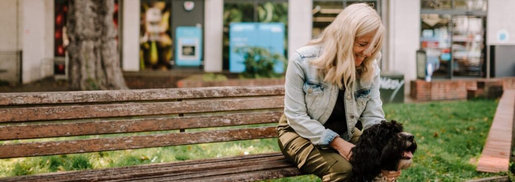 Centre for Better Ageing image - woman in a high street sat on a bench with her dog.