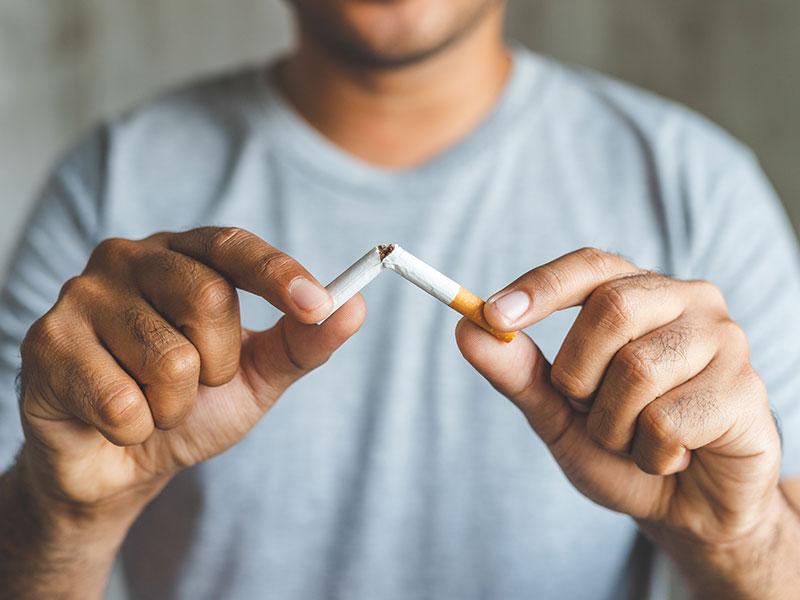 a person snapping cigarette in to two pieces
